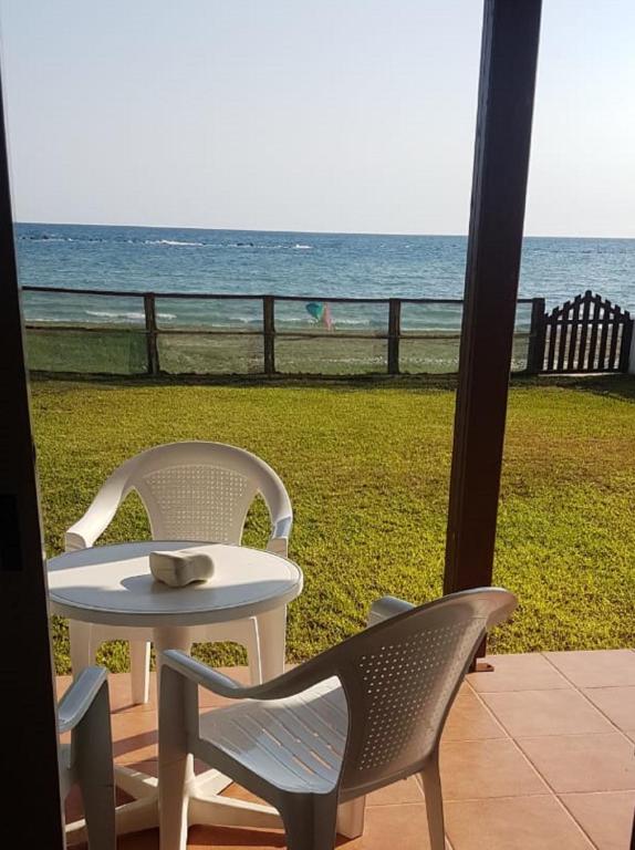 a table and chairs on a porch with a view of the ocean at Panorama Beach House, 5 meters to the sea in Perivolia