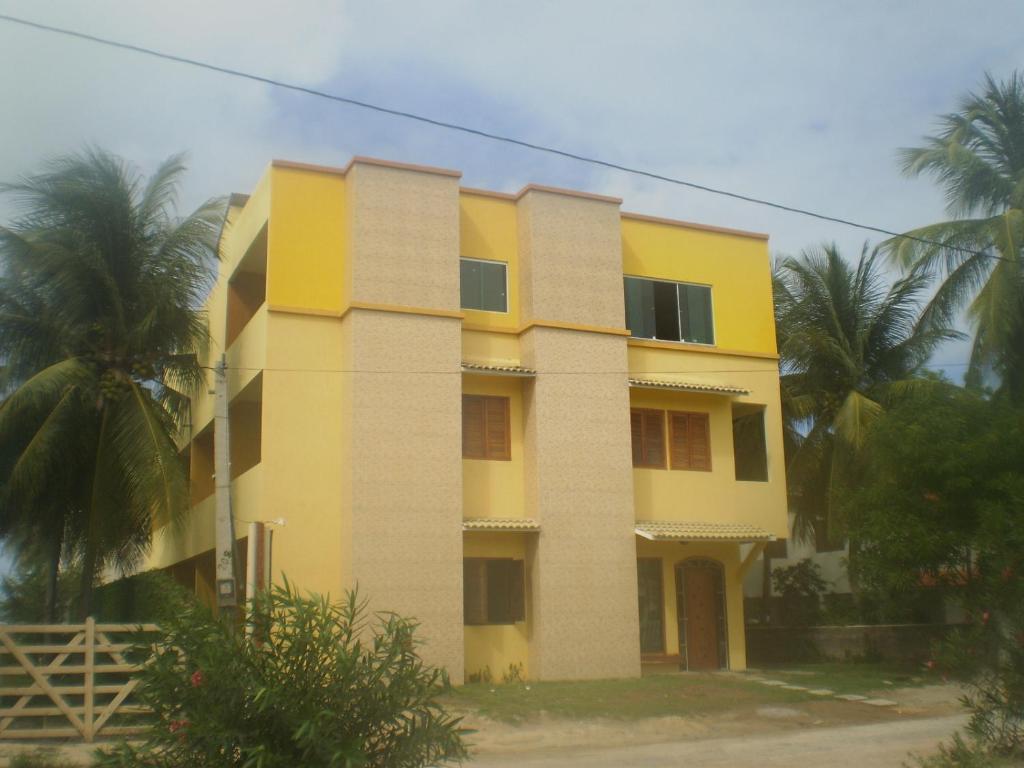 a yellow building with palm trees in front of it at Pousada Costa Coral in Tamandaré