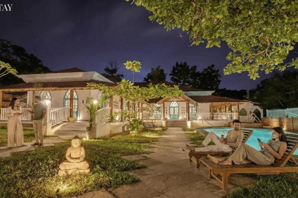 a group of people sitting around a pool at night at EKOSTAY - Blue Tiffany Villa in Nerul