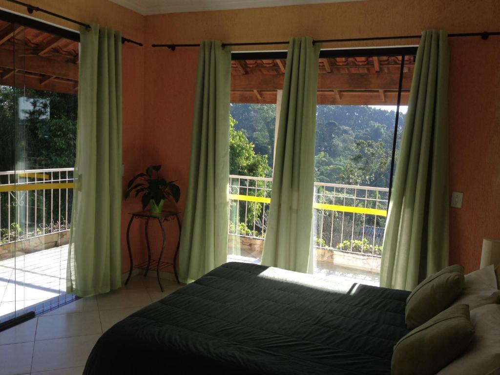 ein Schlafzimmer mit einem Bett und einem großen Fenster in der Unterkunft Pousada Canto das Corujas in São Roque