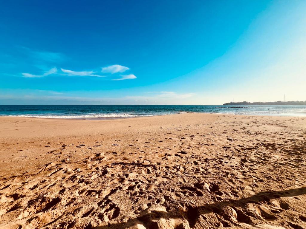 a beach with footprints in the sand and the ocean at Harmony Beach Hotel - Tangalle in Tangalle