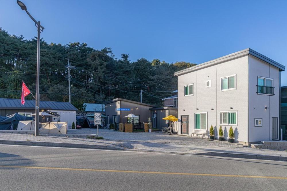a white building on the side of a street at Gangneung SH Pension in Gangneung