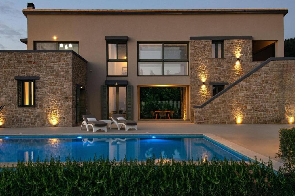 una casa con una piscina di fronte di Villa Cypressa by Villa Plus a Kalamitsi