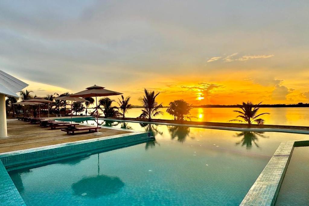 a swimming pool with a sunset in the background at MN Koh Kong Resort in Koh Kong
