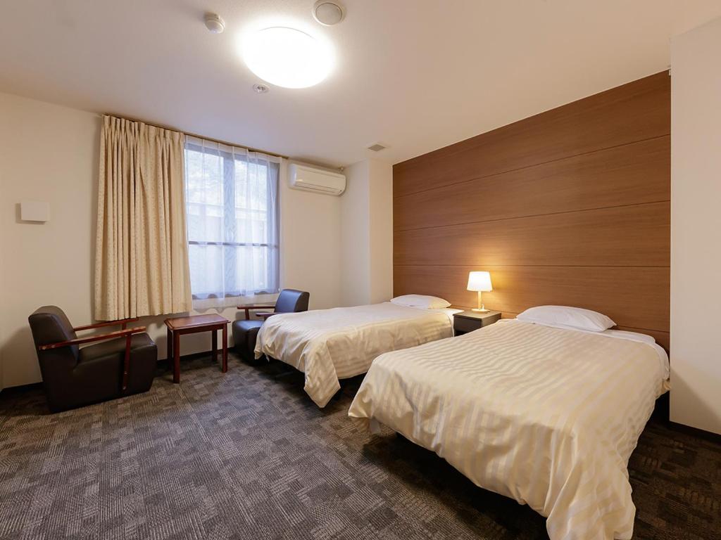 une chambre d'hôtel avec deux lits et une fenêtre dans l'établissement Itoen Hotel Shiobara, à Nasushiobara