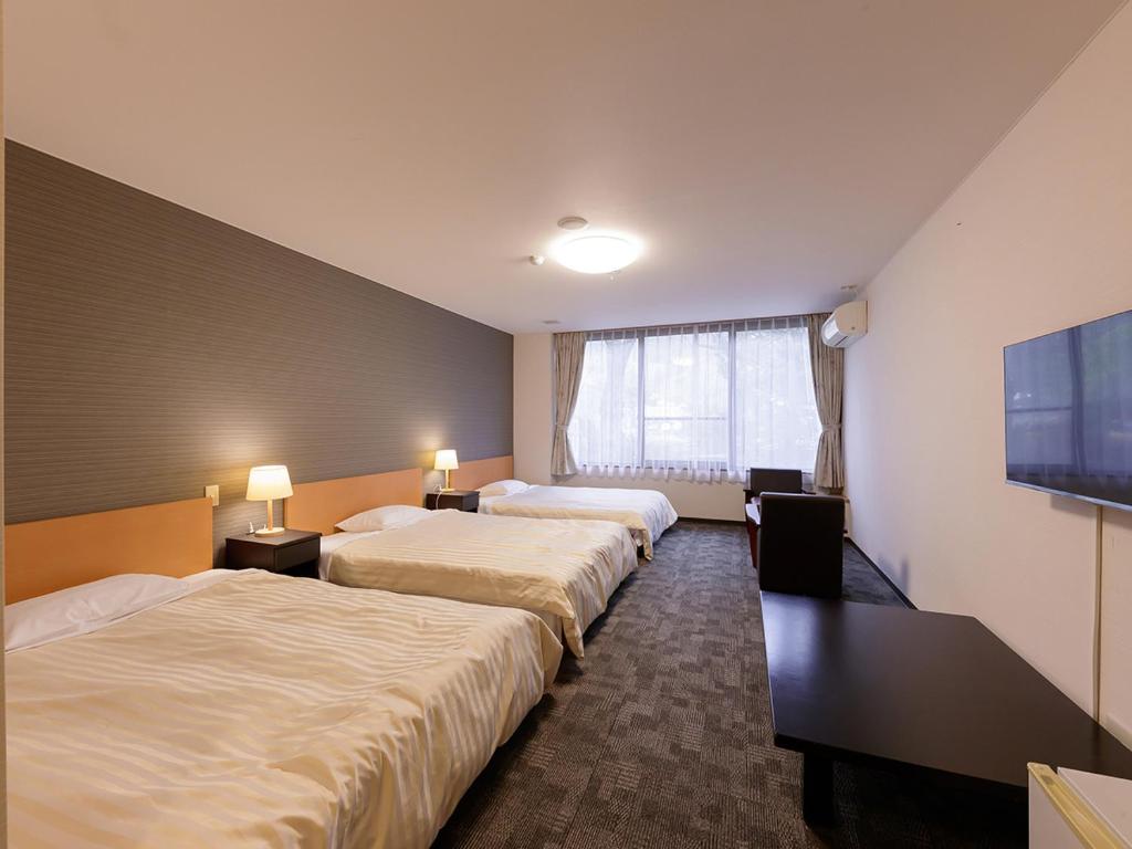 une chambre d'hôtel avec deux lits et une télévision à écran plat dans l'établissement Itoen Hotel Shiobara, à Nasushiobara
