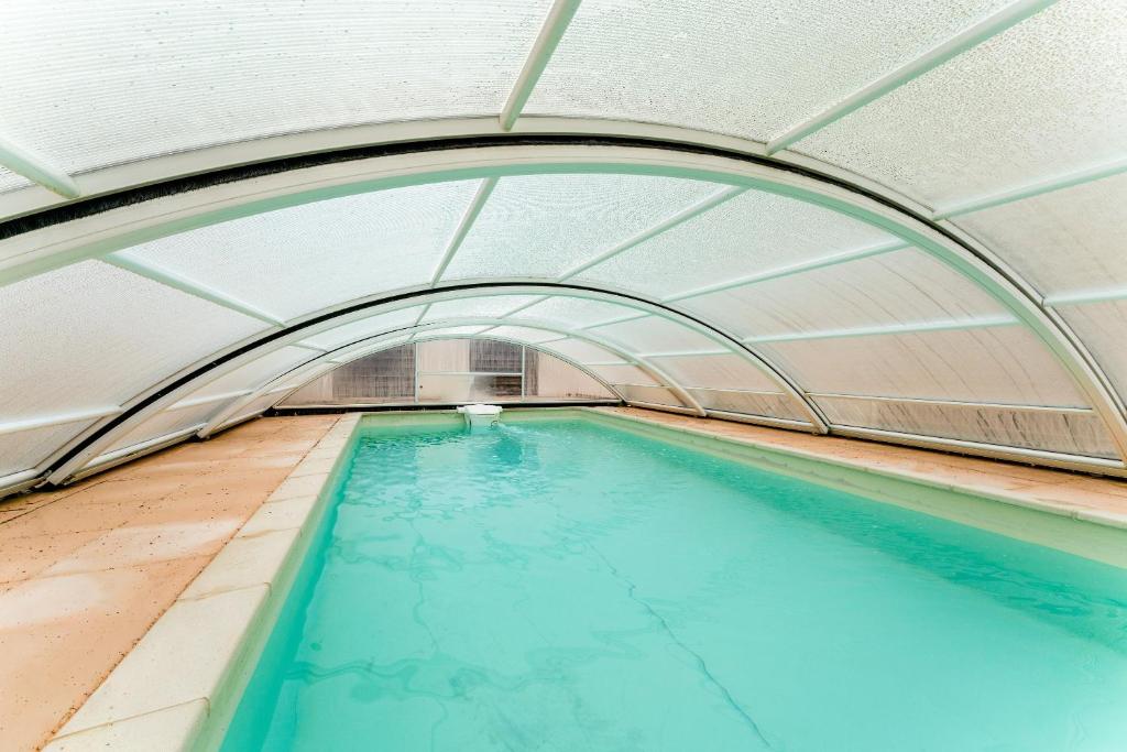 an indoor swimming pool with an archway and blue water at Chambre Bleuet in Piolenc