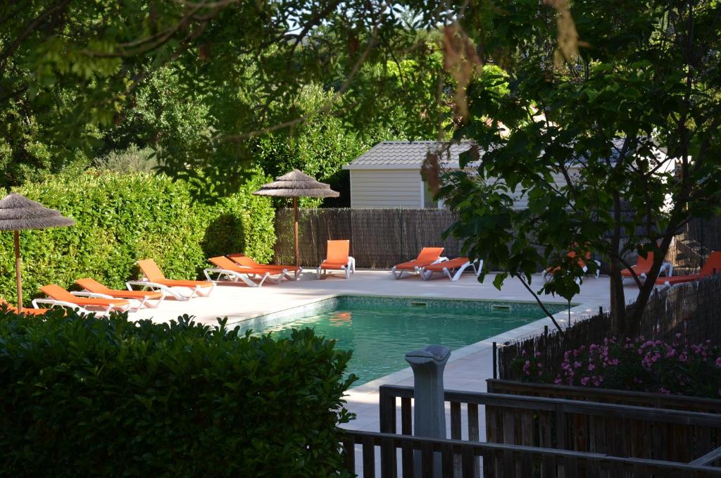 una piscina con sillas y sombrillas naranjas en Camping les Fouguières en Carcès