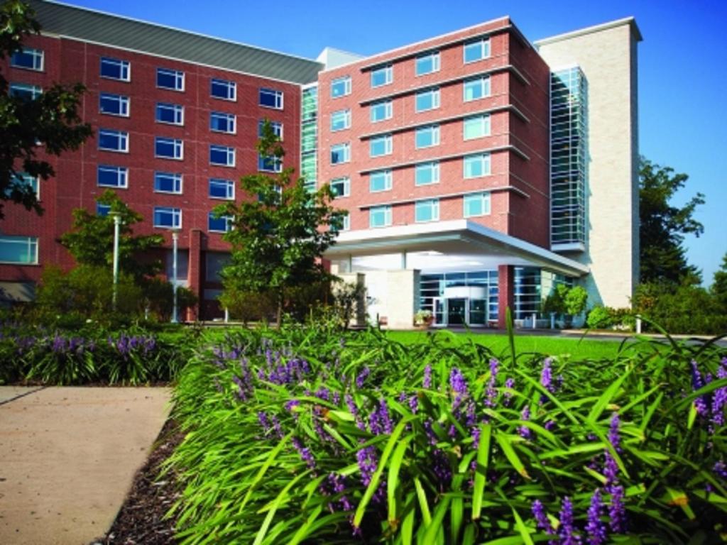 un edificio con fiori viola di fronte a un edificio di The Penn Stater Hotel and Conference Center a State College