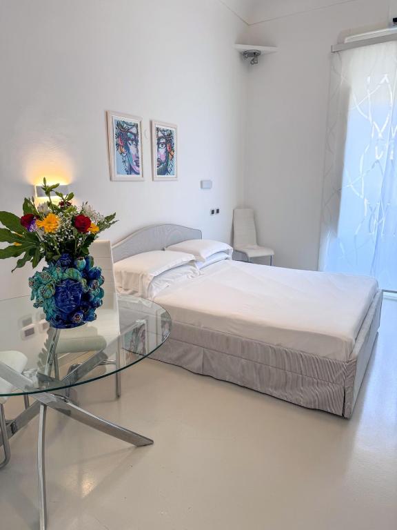 - une chambre avec un lit et une table en verre avec un vase de fleurs dans l'établissement A' Cantunera - Apartment, à Taormine