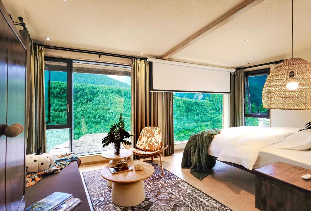 a bedroom with a bed and a large window at Siguniang Mountain Lanxi Wild Luxury Hotel in Mount Siguniang