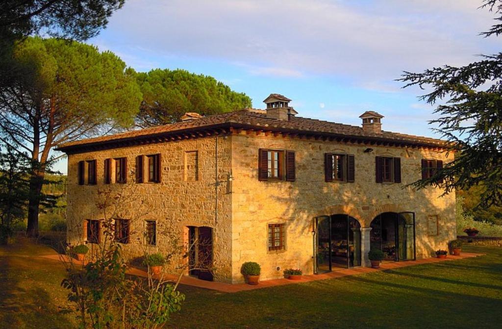 ein großes Steingebäude mit einem Hof und Bäumen in der Unterkunft Podere Lucignano Secondo Agriturismo in Gaiole in Chianti