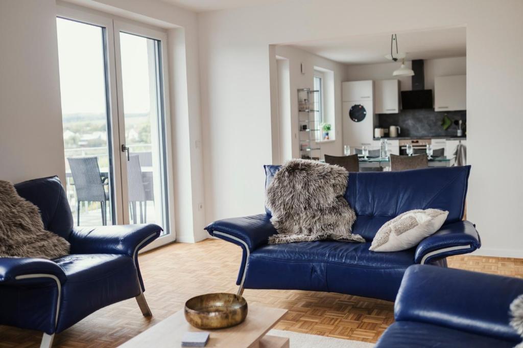 un soggiorno con divano blu e 2 sedie di Ferienwohnung Schwalbenflug a Naumburg
