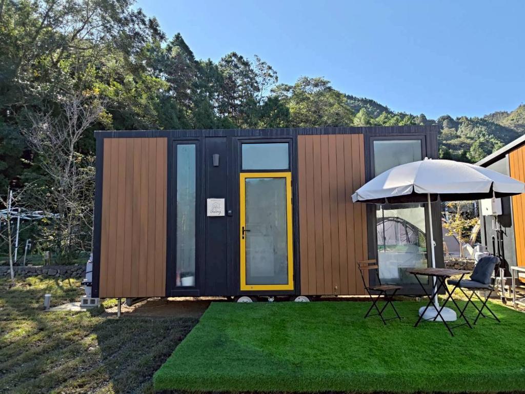 a tiny house with a table and an umbrella at Forest Star Cottage X by Tiny Away in Hsin-ch'eng