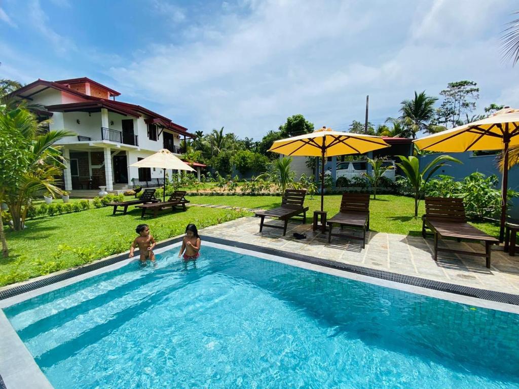 twee kinderen staan in een zwembad in een resort bij Nelumbo Villa 42 - oasis of relaxations in Uragasmanhandiya