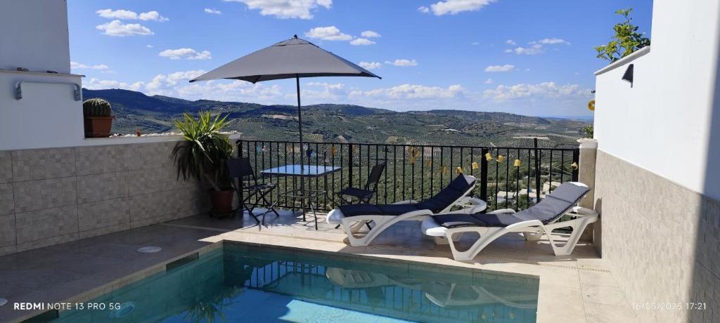 un par de sillas y una sombrilla junto a una piscina en Casa Rural Emma, en Zuheros