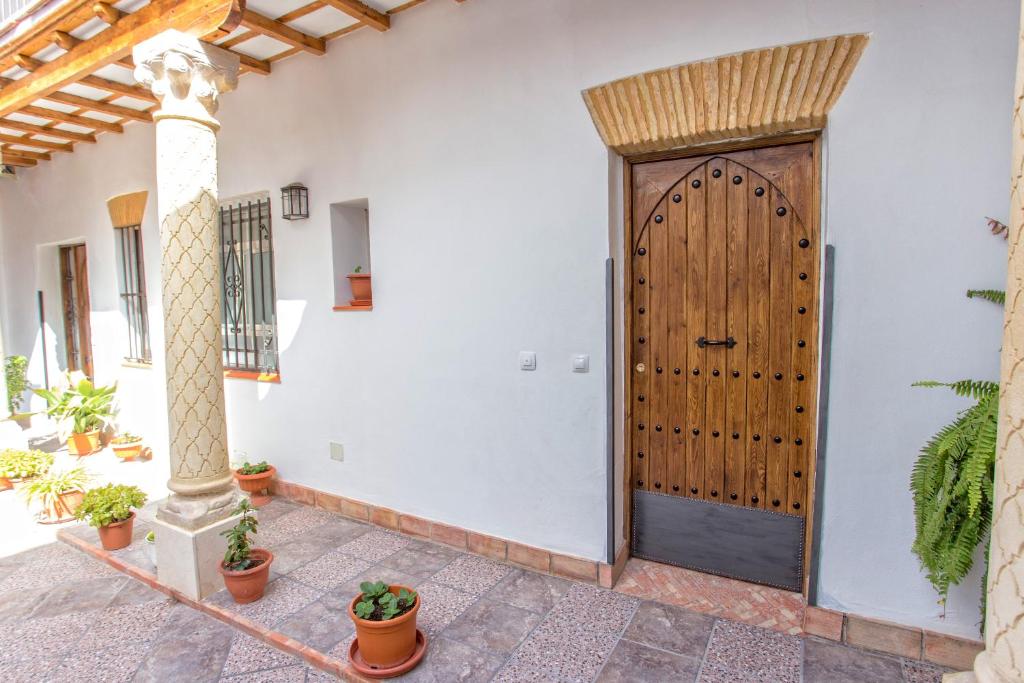 a wooden door in a white wall with potted plants at Multi Apartamentos La Kasbah in Jerez de la Frontera