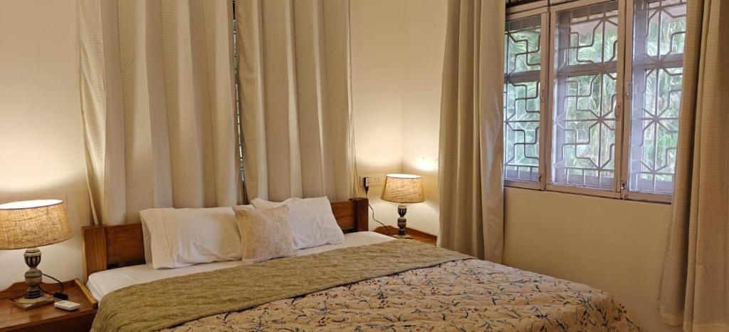 ein Schlafzimmer mit einem Bett mit zwei Lampen und einem Fenster in der Unterkunft Amore Holiday Home in Canacona