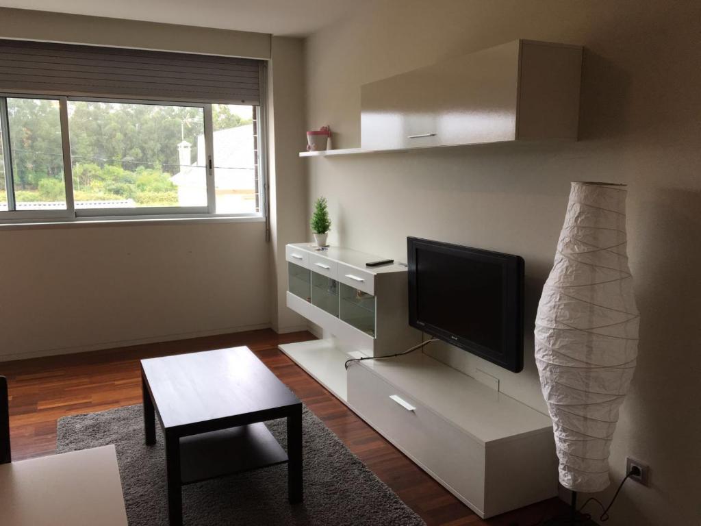 uma sala de estar com uma televisão de ecrã plano e uma mesa em Apartamento Alvaro em Isla de Arosa