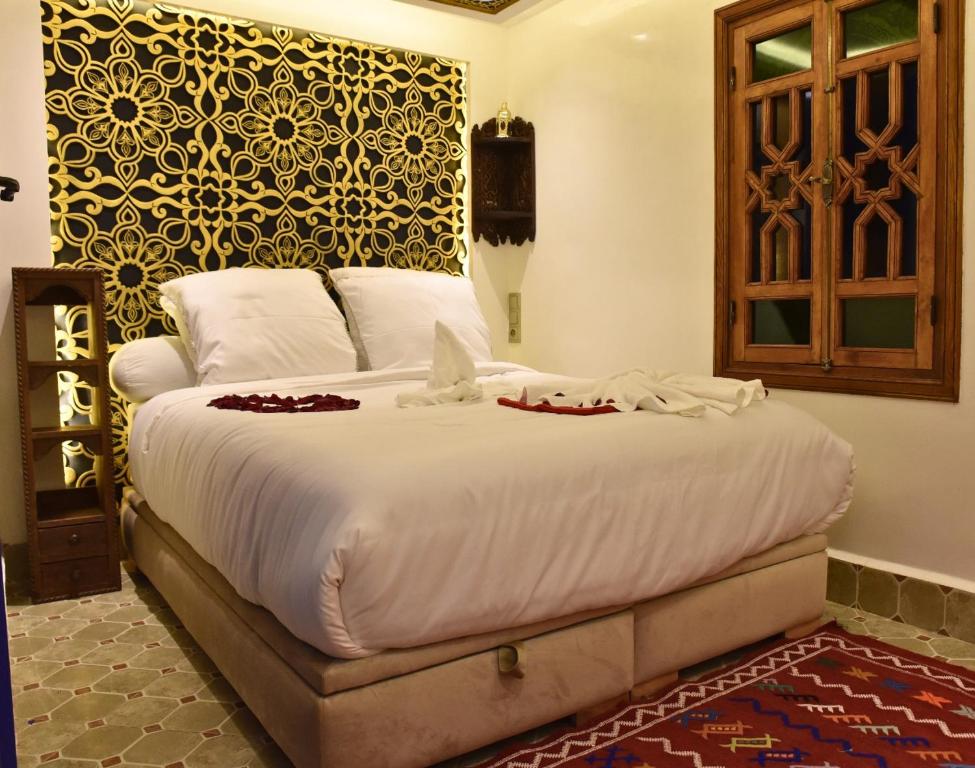 マラケシュにあるRiad Lilou Marrakechのベッドルーム1室(白いシーツと赤い花のベッド付)