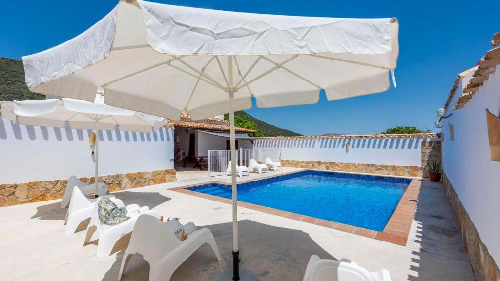 a swimming pool with an umbrella and chairs and a pool at Cortijo El Llano Priego de Córdoba by Ruralidays in Priego de Córdoba