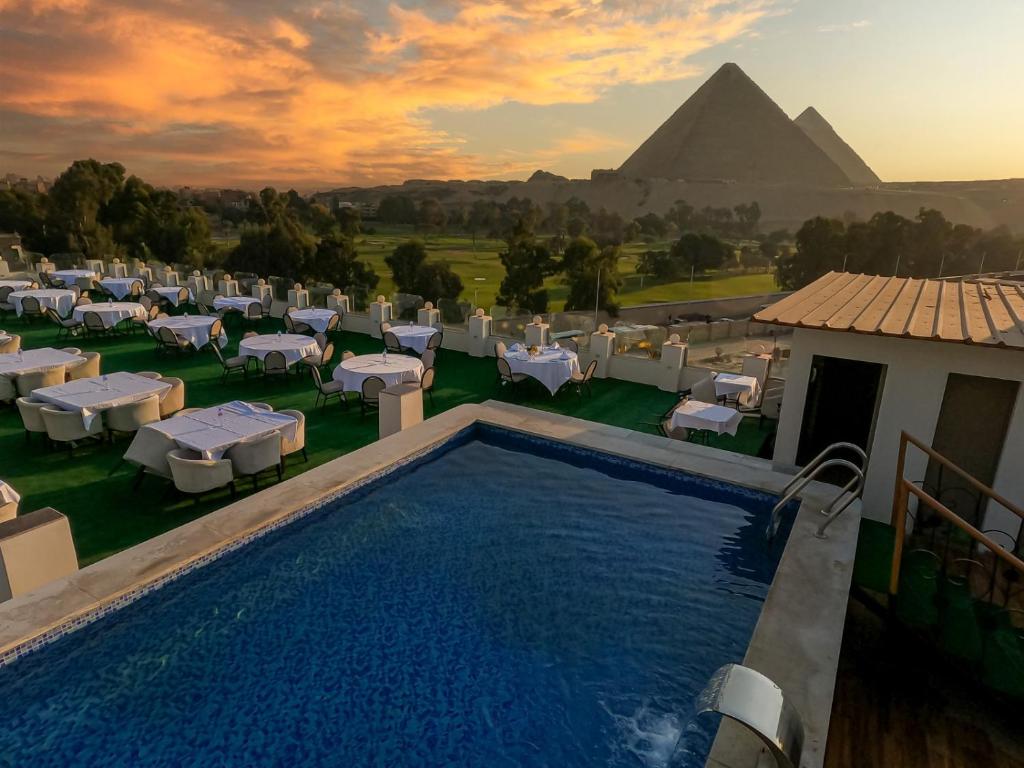 Un complejo turístico con piscina y pirámide al fondo. en Sahary Pyramids View Hotel, en Giza