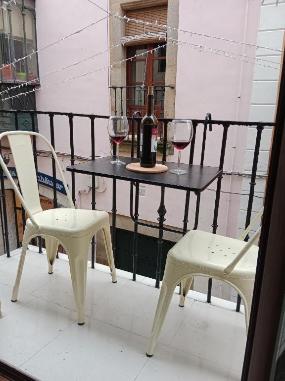 a table with two chairs and a bottle and two glasses of wine at Casa Mencía in Plasencia