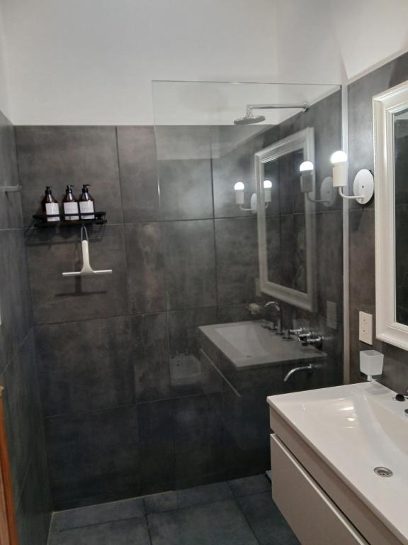ein Badezimmer mit Waschbecken und Dusche in der Unterkunft Farrell Jardin - Casco Historico in San Antonio de Areco