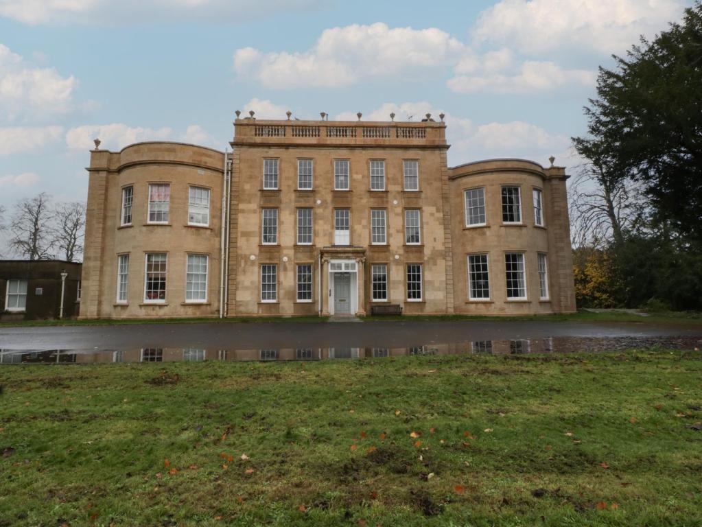 een oud gebouw met een grasveld ervoor bij Frenchay Park House in Bristol