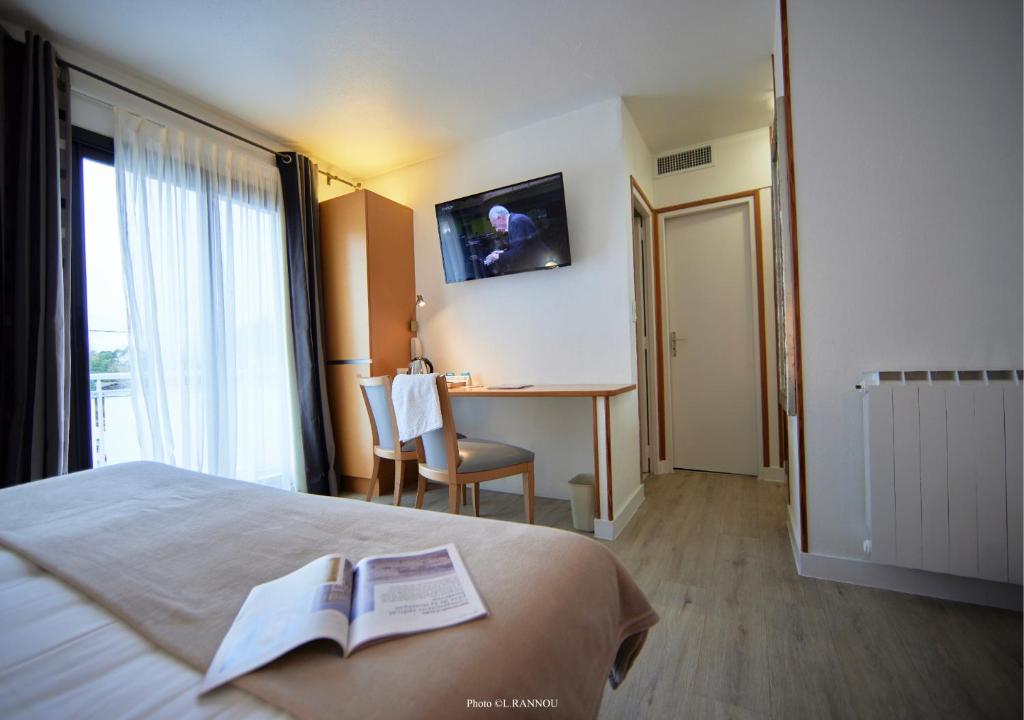 a hotel room with a bed and a table with a book at Logis Le Gavrinis in Baden