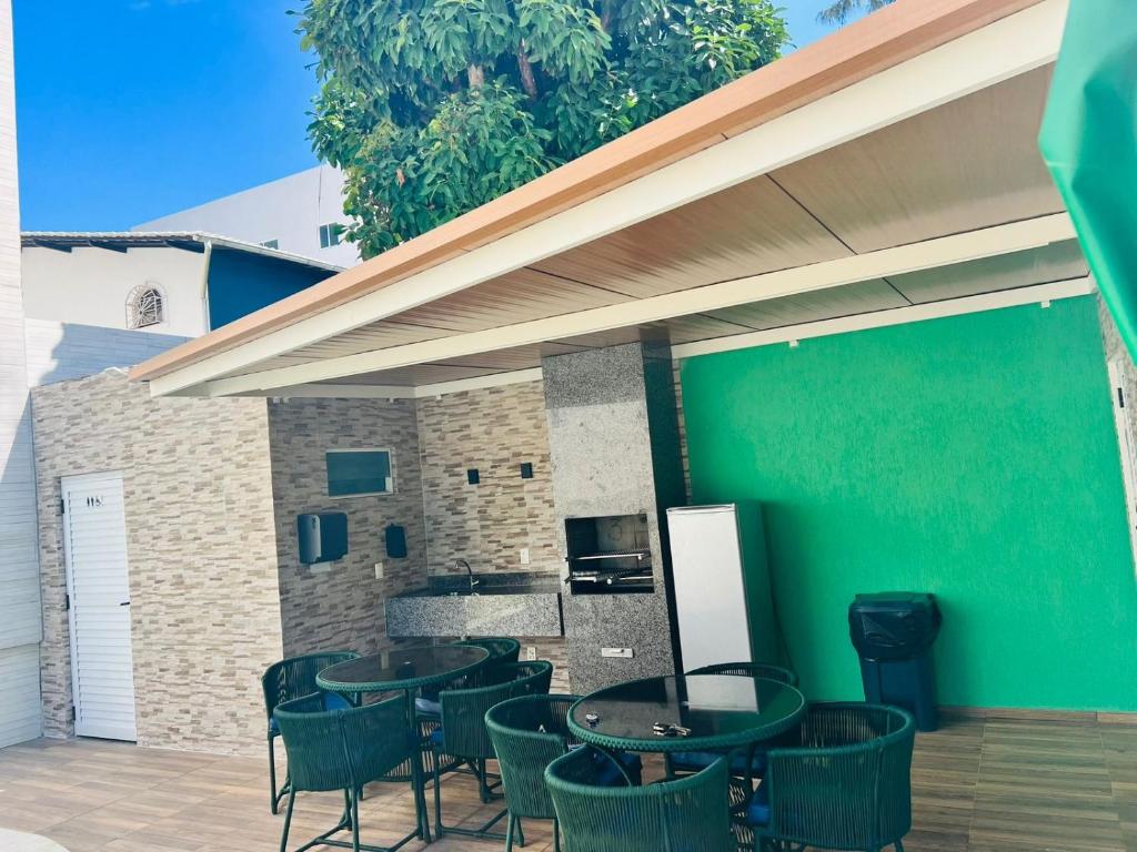 a patio with tables and chairs and a green wall at La Coruña Flat Makaranduba in Porto De Galinhas