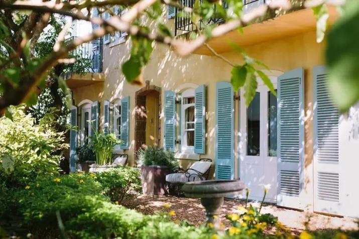 una casa con le persiane blu e una panchina nel cortile di Auberge Burgundy Boutique Hotel & Spa a Hermanus