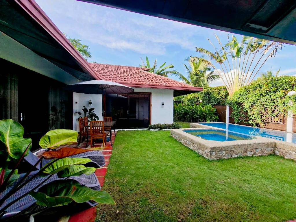 een achtertuin met een zwembad en een huis bij Villas Flora Bella Resort in Dauis