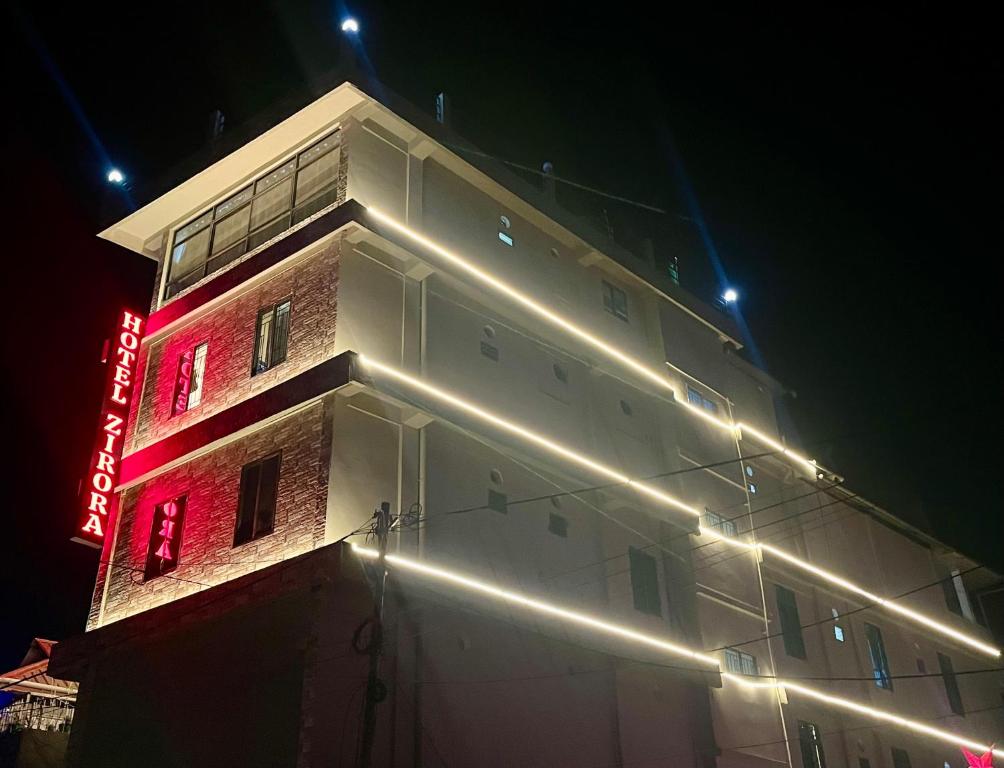 a building with a neon sign on the side of it at Hotel Zirora in Ziro