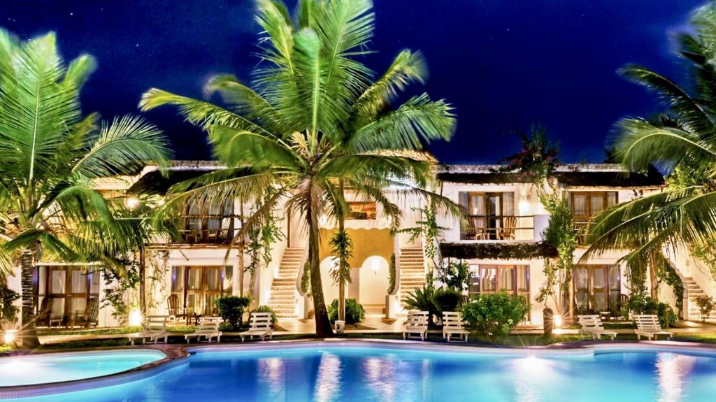 a resort with a pool and palm trees at night at My Blue Hotel Zanzibar in Nungwi