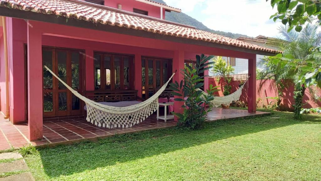 een rood huis met hangmatten op de veranda bij Ubatuba Surf Hostel, apenas a 60 metros da praia da Lagoinha! in Ubatuba