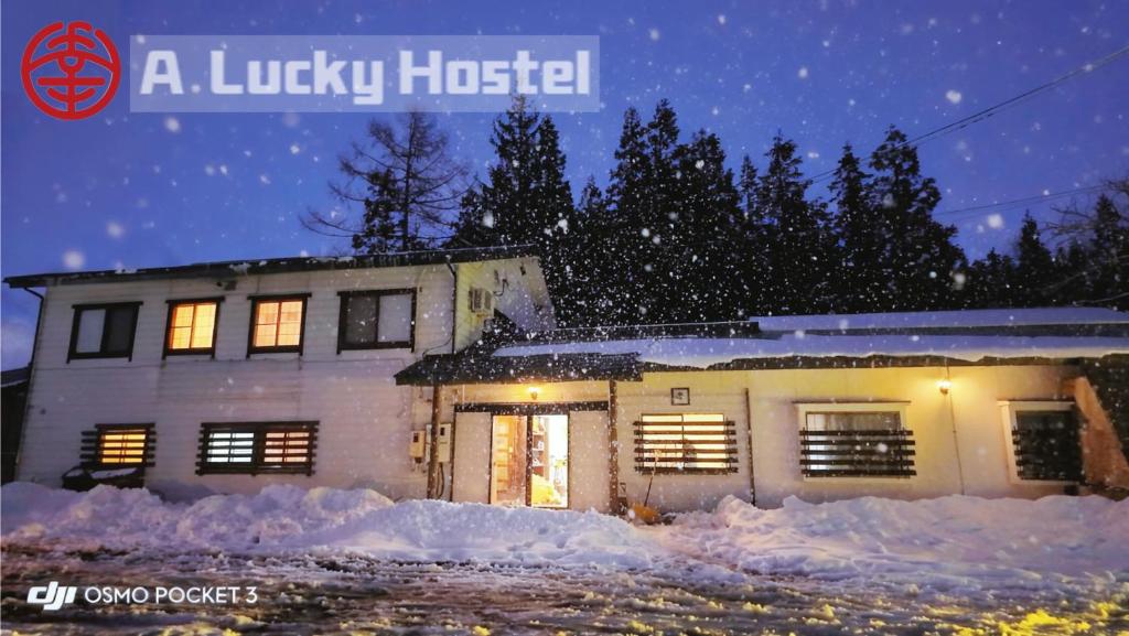 Una casa en la nieve por la noche en A Lucky Hostel, en Hakuba