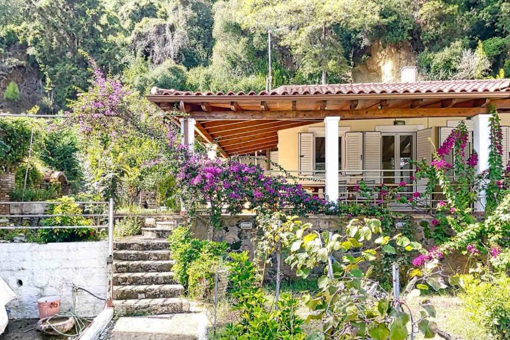 Una casa con flores y escaleras delante. en Demar Rooms & Apartments, en Katakolon