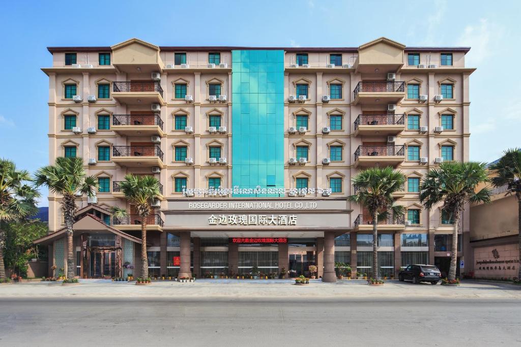 a large building with palm trees in front of it at Rose Garden International Hotel in Phnom Penh