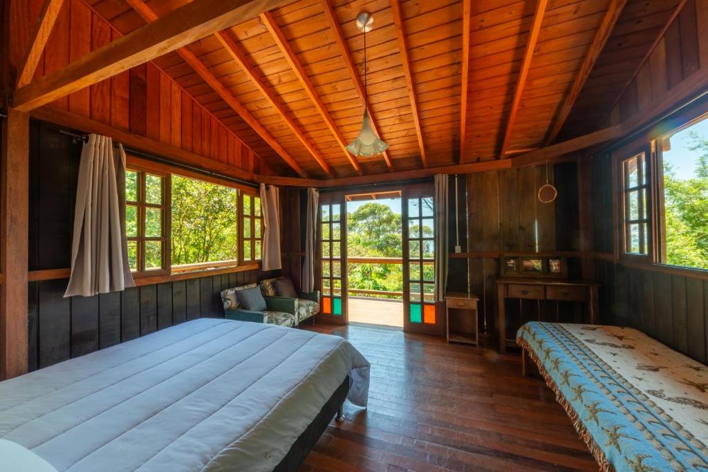 a bedroom with a large bed and windows at Coração da Terra Praia do Rosa in Praia do Rosa