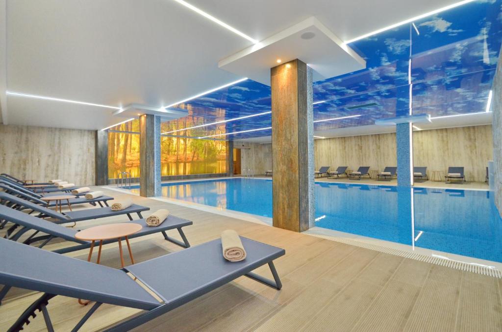 a swimming pool with blue tables and chairs next to it at Hotel Aleksandar Conference & Spa in Žabljak