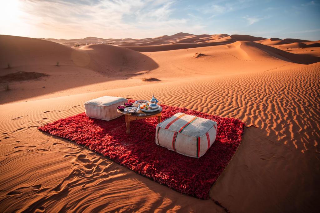 a desert scene with two beds in the desert at Merzouga dunes erg chabbi Camp in Merzouga