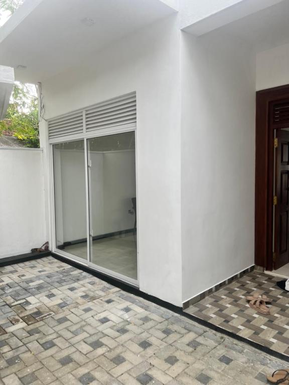 um quarto vazio com portas de vidro e piso de azulejo em Kaushi Home em Kottawa
