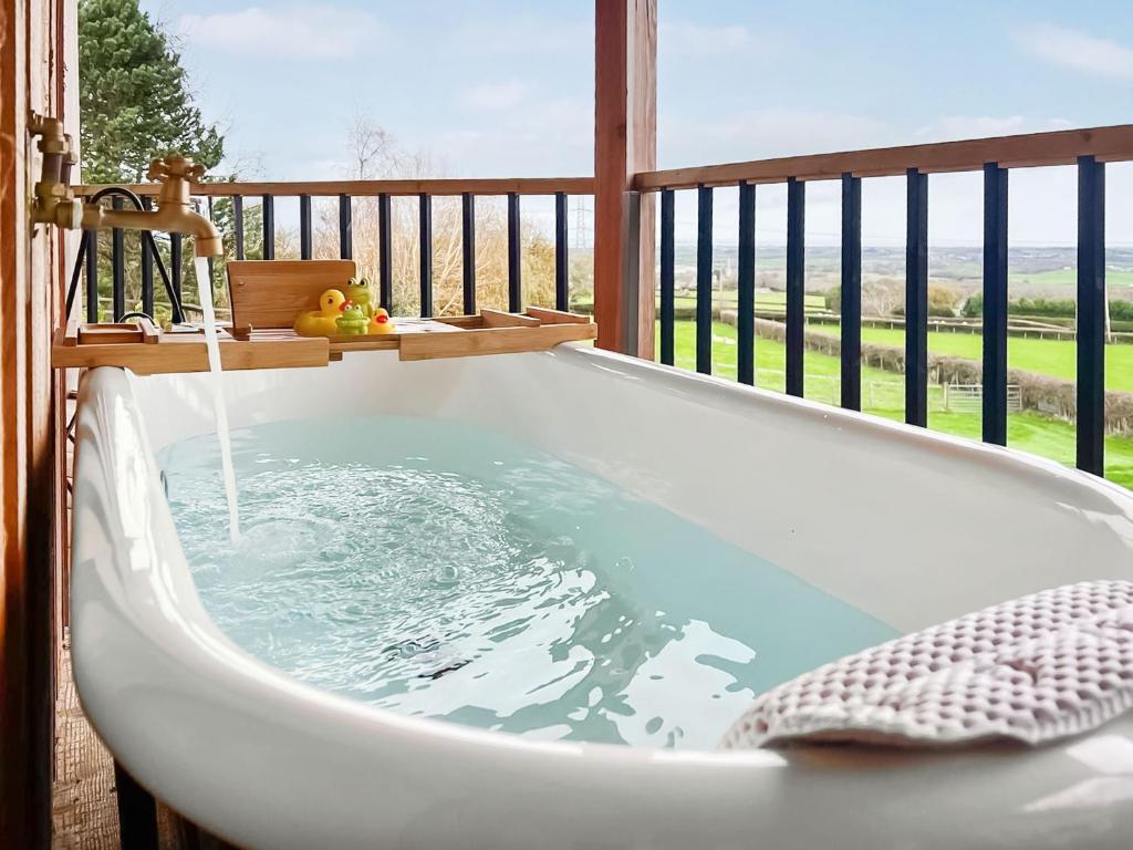 eine Badewanne auf einem Balkon mit Meerblick in der Unterkunft The Rabbit Hole - Uk50123 in Bodelwyddan