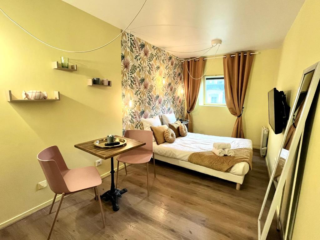 une petite pièce avec un lit, une table et des chaises dans l'établissement la bonbonnière Jaune, à Caen