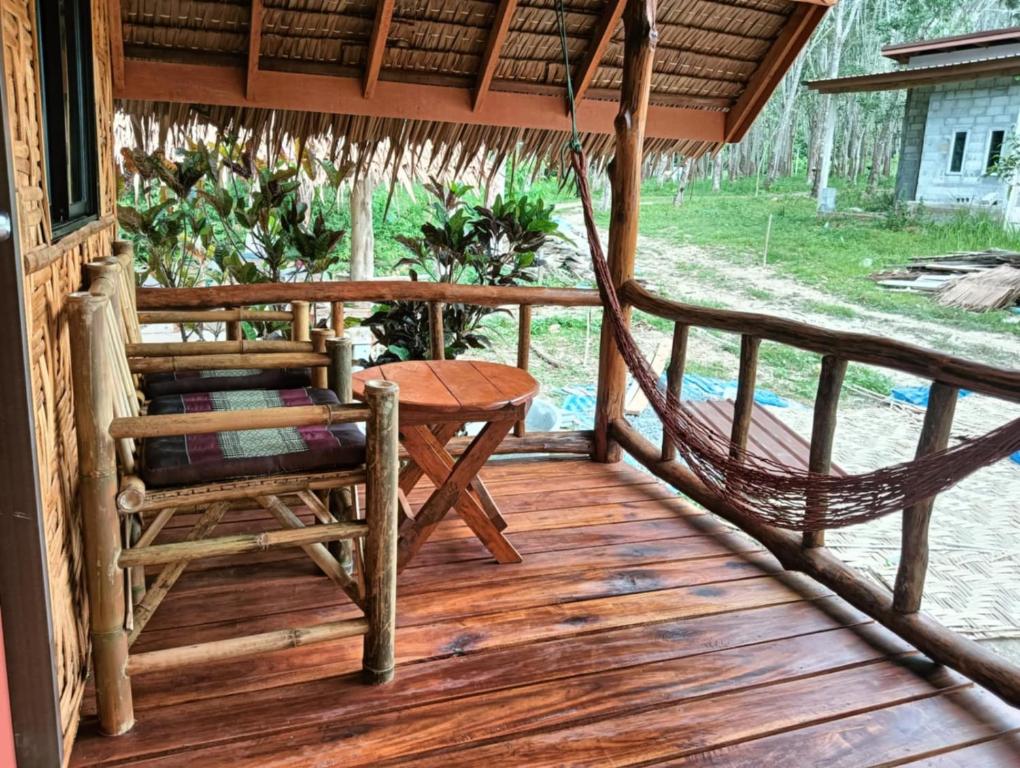 een veranda met een hangmat en een tafel en stoelen bij Bansuan Lanta Maikaew in Koh Lanta