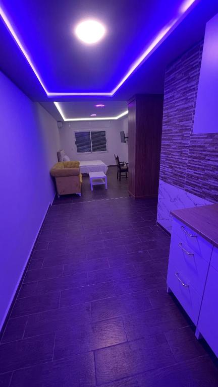 uma sala de estar com iluminação roxa e um sofá em Suits Mirasol em Tânger