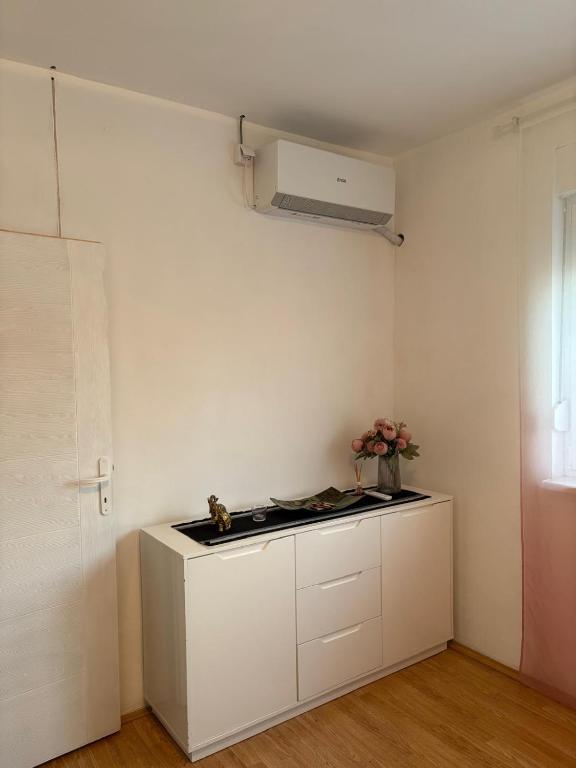 a white kitchen with a stove and a vase of flowers at Apartman Tijana in Ruma