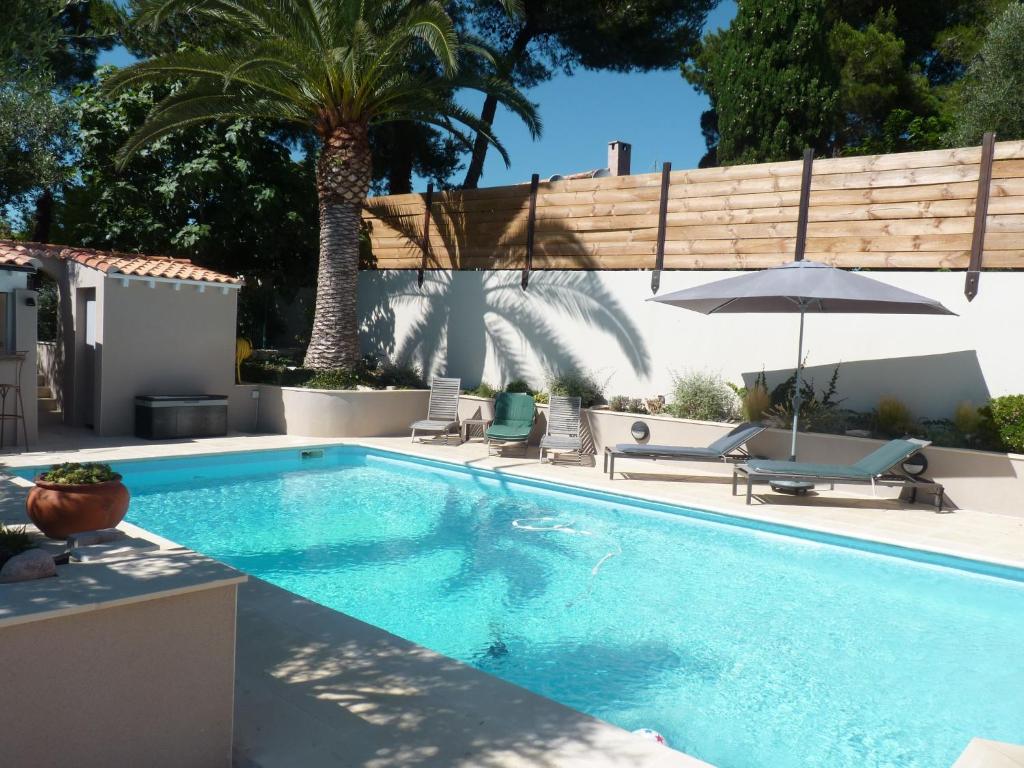 - une piscine avec 2 chaises et un parasol dans l'établissement La Villa du Petit Port, à Martigues