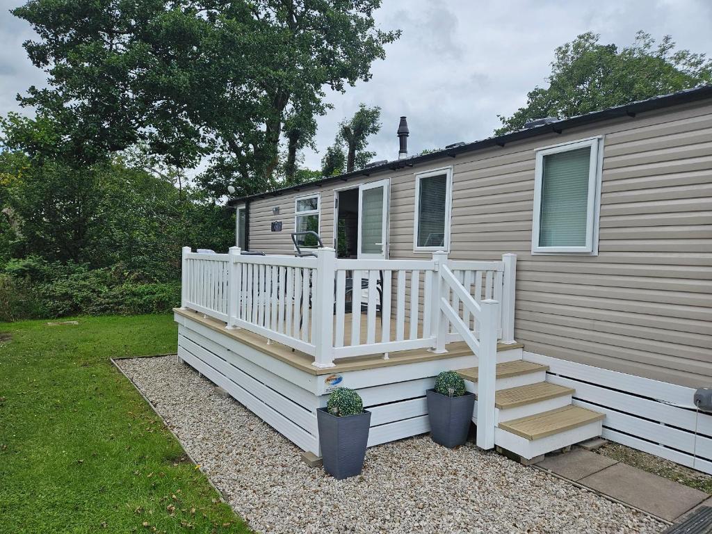 a mobile home with a white deck and stairs at Woodland View in Skipton